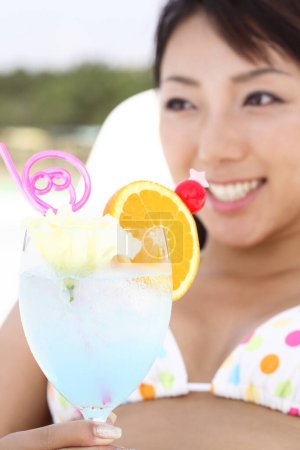 Foto de Mujer asiática bebiendo un cóctel en una playa - Imagen libre de derechos