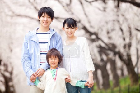 Téléchargez les photos : Portrait de la famille japonaise heureuse dans le parc de printemps - en image libre de droit