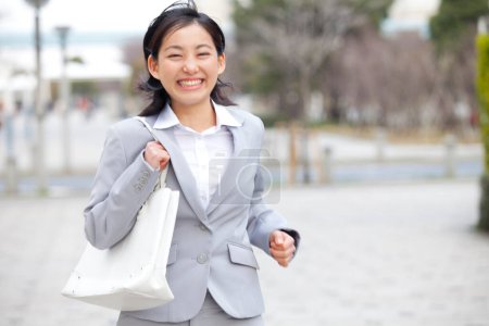 Téléchargez les photos : Une femme en costume d'affaires courant dans la rue - en image libre de droit