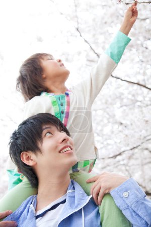Foto de Feliz padre e hijo japonés disfrutando de la primavera en el parque - Imagen libre de derechos