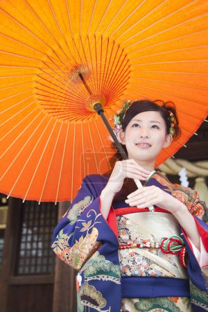 Téléchargez les photos : Belle jeune femme japonaise en costume traditionnel au temple avec parapluie en papier antique - en image libre de droit