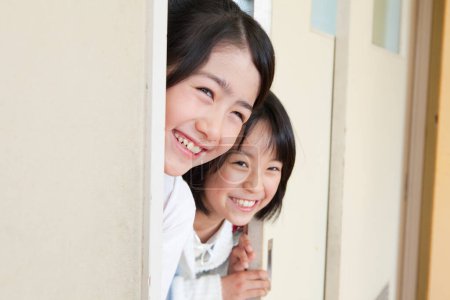 Téléchargez les photos : Portrait de heureux asiatique écolières entrant salle de classe - en image libre de droit