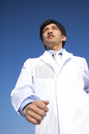 Téléchargez les photos : Un homme en blouse de laboratoire et cravate marche outdiirs - en image libre de droit