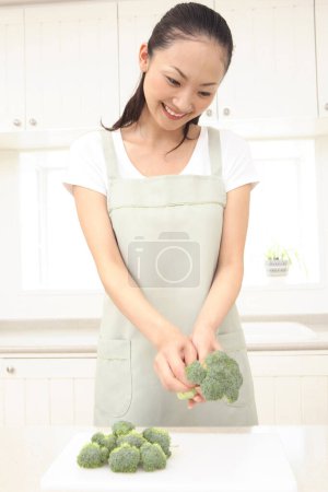 Photo for Beautiful Asian housewife cooking in kitchen - Royalty Free Image