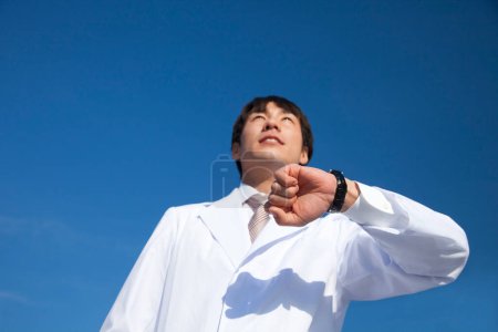 Foto de Un hombre con bata de laboratorio mirando el reloj - Imagen libre de derechos
