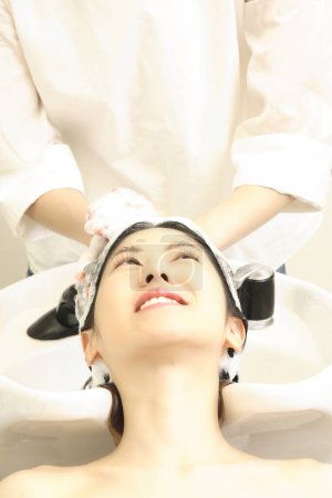 Téléchargez les photos : Portrait de femme japonaise souriante se lavant la tête chez le coiffeur - en image libre de droit