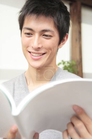 Téléchargez les photos : Asiatique mâle étudiant avec livre à la maison - en image libre de droit