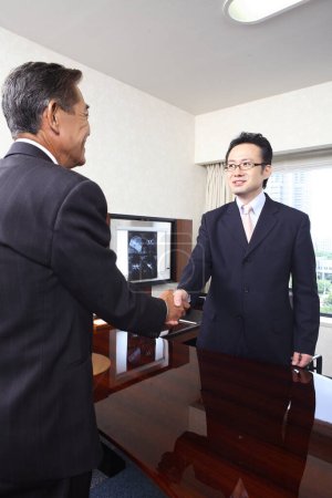 two confident japanese professors shaking hands in office