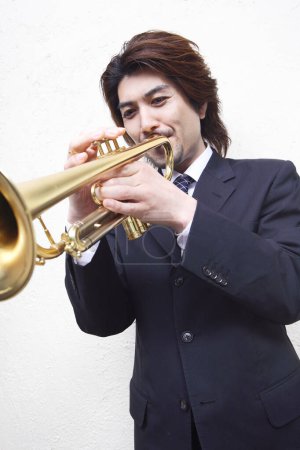 Téléchargez les photos : Asiatique homme en costume jouer avec trompette - en image libre de droit