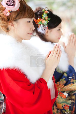 Asian girls dressed in furisode praying in temple