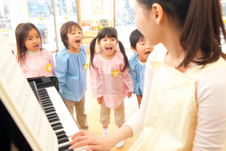Foto de Grupo de niños de pie y cantando alrededor del piano - Imagen libre de derechos