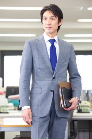 Foto de Un hombre con traje y corbata sosteniendo una carpeta - Imagen libre de derechos