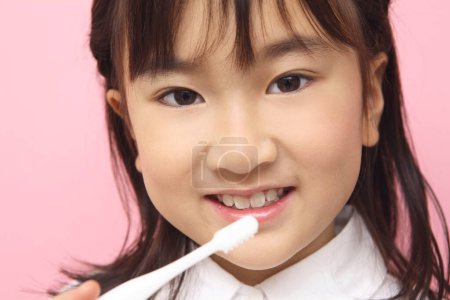 Foto de Asiático niña con un cepillo de dientes cepillarse los dientes - Imagen libre de derechos