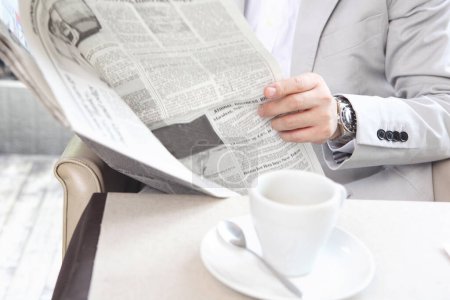 Foto de Un hombre leyendo un periódico mientras está sentado en una mesa - Imagen libre de derechos