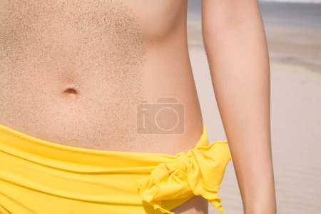 Photo for Cropped photo of woman wearing yellow swimsuit standing on beach - Royalty Free Image