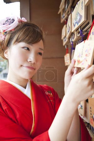 Foto de Hermosa japonesa mujer en kimono holding ema en santuario. - Imagen libre de derechos