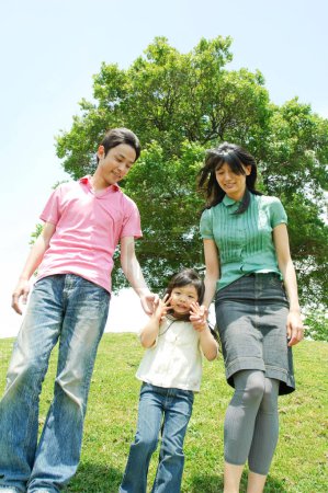Téléchargez les photos : Portrait d'une jeune famille avec enfant marchant dans le parc - en image libre de droit