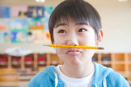 Téléchargez les photos : Portrait de jeune asiatique garçon dans salle de classe à l'école - en image libre de droit