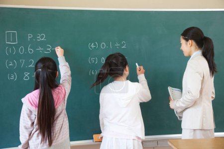 Téléchargez les photos : Japonais écolières et enseignant faire des exercices sur tableau noir à l'école - en image libre de droit