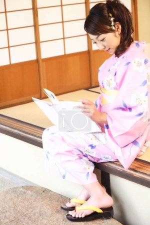 Téléchargez les photos : Une femme en kimono lisant un livre - en image libre de droit