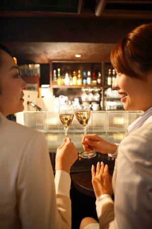 Photo for Young female friends with glasses of champagne resting in restaurant - Royalty Free Image