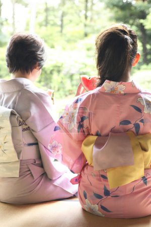 Téléchargez les photos : Japonais femmes en kimono manger pastèque, vue de dos - en image libre de droit