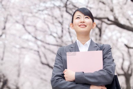 Téléchargez les photos : Portrait de belle jeune femme d'affaires japonaise avec dossier de documents dans le parc pendant la saison des fleurs sakura - en image libre de droit