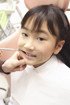 Téléchargez les photos : Japonaise assise sur une chaise de dentiste. Concept de traitement dentaire - en image libre de droit