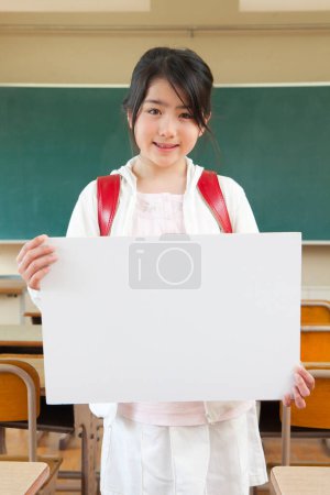 Photo for Smiling young student with blank paper placard in classroom - Royalty Free Image