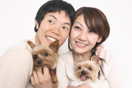 a man and woman holding two small dogs
