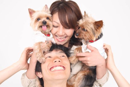 a woman holding two small dogs on man's shoulders