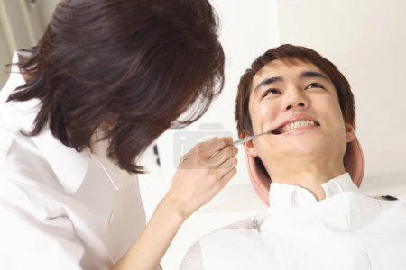 Téléchargez les photos : Jeune asiatique homme obtention son dents traitement à dentiste bureau - en image libre de droit