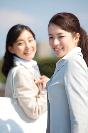 Photo for Two asian business women smiling and posing for a picture - Royalty Free Image