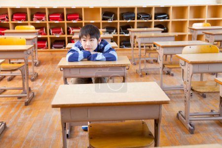 Foto de Aburrido japonés escuela chico sentado en clase - Imagen libre de derechos