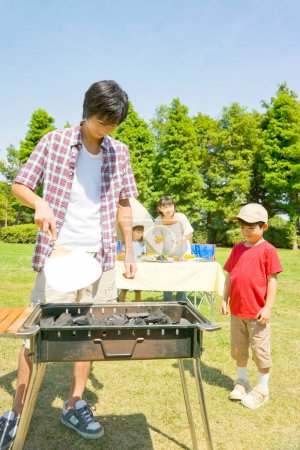 Téléchargez les photos : Heureux japonais jeune famille faire barbecue dans camp - en image libre de droit