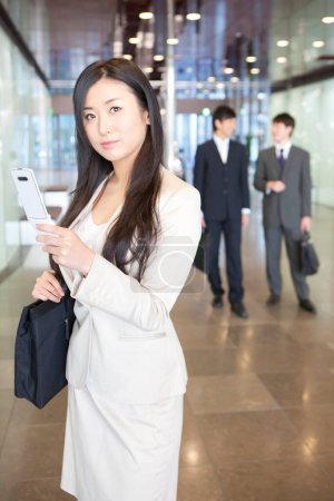 Foto de Una mujer con un traje blanco sosteniendo un teléfono celular - Imagen libre de derechos