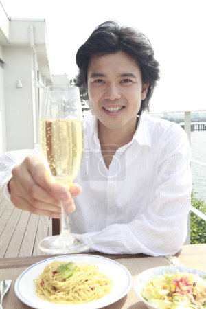 Téléchargez les photos : Young man drinking champagne in the cafe - en image libre de droit