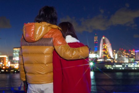 Photo for Back view of couple in winter clothes looking at city, blurred background - Royalty Free Image