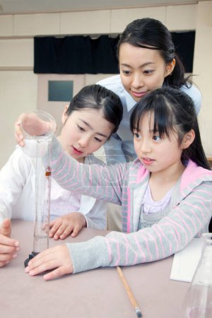 Photo for Japanese elementary school children doing chemical experiment with teacher in classroom - Royalty Free Image