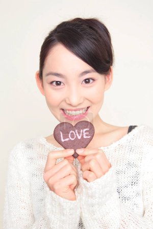 Téléchargez les photos : Jeune asiatique japonais femme tenant coeur en forme de cookie - en image libre de droit