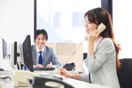 Photo for A woman talking on a phone while sitting at a desk - Royalty Free Image