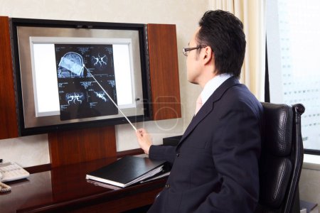 Téléchargez les photos : Médecin japonais examinant des images radiographiques de patients - en image libre de droit