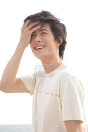 Téléchargez les photos : Sourire jeune asiatique homme contre bleu ciel - en image libre de droit