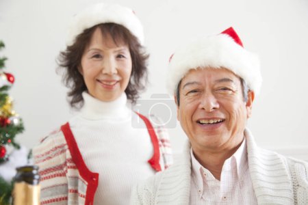 Photo for Asian senior  couple looking at camera  celebrating Christmas at home - Royalty Free Image