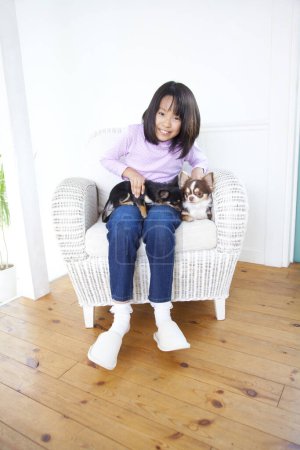 Téléchargez les photos : Japonais fille assis dans le fauteuil avec Chihuahua chiens - en image libre de droit