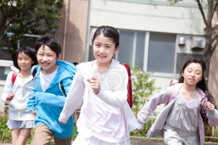 Téléchargez les photos : Groupe d "élèves heureux de l" école primaire qui courent sur la cour de l "école - en image libre de droit