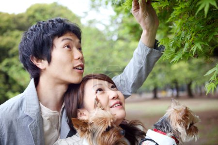 Téléchargez les photos : Un homme et une femme tenant un chien dans un parc - en image libre de droit