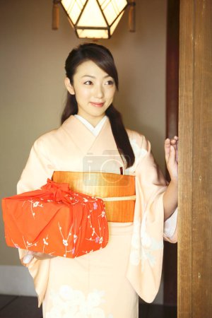 Téléchargez les photos : Portrait de jeune femme japonaise en kimono traditionnel tenant un bento enveloppé - en image libre de droit