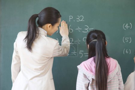Téléchargez les photos : Japonais écolière et enseignant faire des exercices sur tableau noir à l'école - en image libre de droit