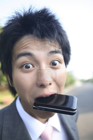 Photo for A man with a cell phone in his mouth - Royalty Free Image